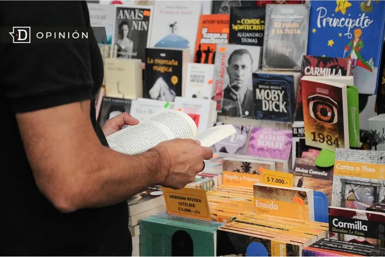16009 hombre leyendo un libro frente a un stand con mas libros.webp