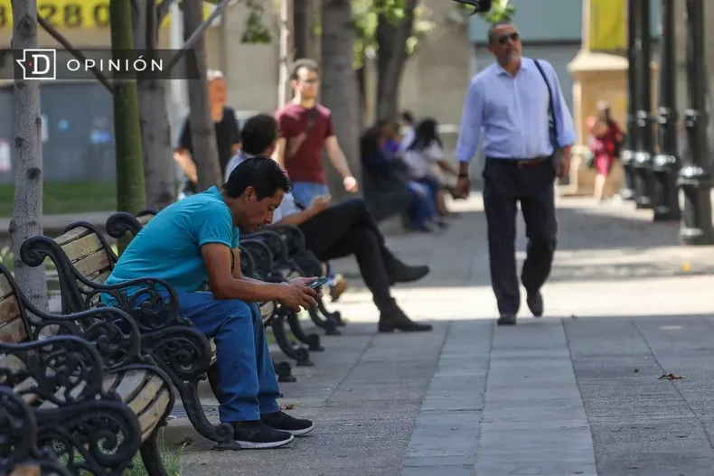 19077 personas sentadas en una banca y otras caminando.webp