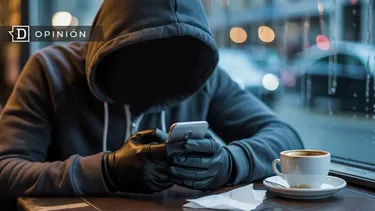 El Desconcierto | 22577 persona con capucha viendo su celular en un cafe.webp