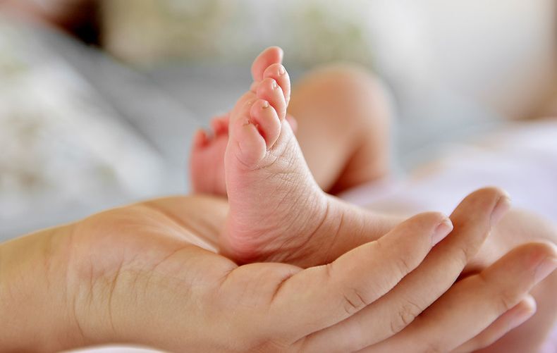 Imagen de la mano de una madre sosteniendo el pie de su bebé / Agencia Uno