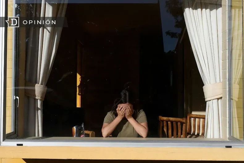 28593 una mujer en una ventana cubriendose el rostro con las manos.webp