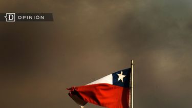 El Desconcierto | 8514 bandera chilena ondeando en un cielo cubierto por humo negro.jpg
