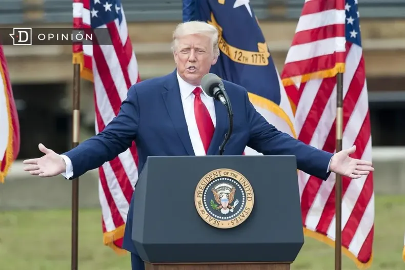 24963 donald trump en un podio con banderas de usa de fondo.webp