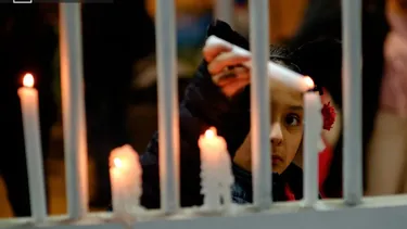 El Desconcierto | 22439 nina prendiento unas velas en una reja.webp