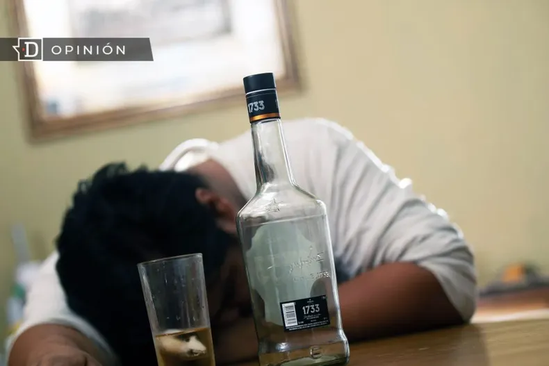 21959 hombre inconsciente con una botella de pisco al frente.webp
